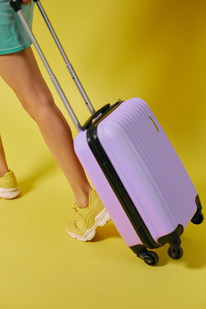 Stylish woman pulling a purple suitcase against a vibrant yellow backdrop. Perfect for travel themes.