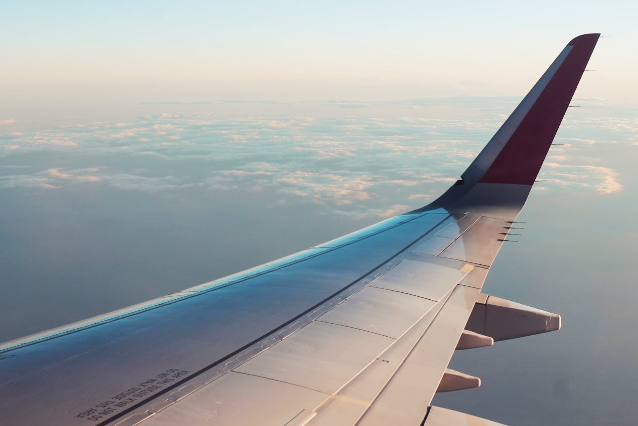 A breathtaking view from an airplane window showcasing clouds and a wing tip over a serene sky.