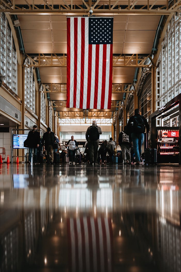 Travelers walk under an American flag in the atrium of Reagan Airport, Washington D.C.